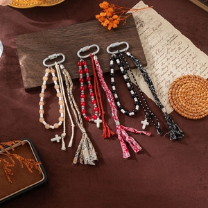 Bohemian bead keychain with floral tassel and cross pendant on vintage background