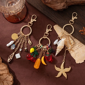 Fashionable 14K gold plated keychains with charms including pearls, fruits and sea stars