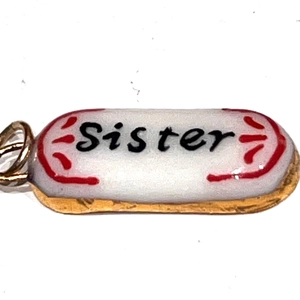 Vue macro d'un pendentif capsule en acier inoxydable avec texte Sister et accents rouges