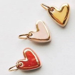 Three colorful enamel heart pendants in gold, pink, and red for DIY jewelry making