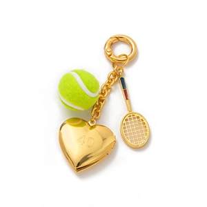 Détail d'un porte-clés tennis doré avec balle en peluche, raquette et médaillon coeur