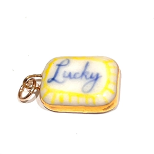 Détail d'un pendentif rectangulaire avec lettrage Lucky et bords en acier doré 18 carats