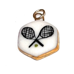 Vue détaillée du pendentif hexagonal doré avec motif de raquette et balle de tennis