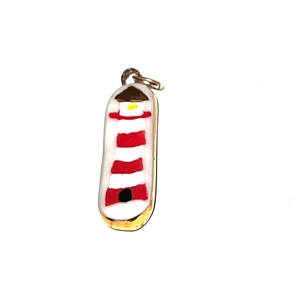 Détail d'un pendentif phare nautique en émail rouge et blanc sur acier inoxydable doré