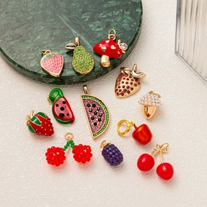 Vue macro de divers pendentifs en forme de fruits dorés avec détails émaillés et cristal