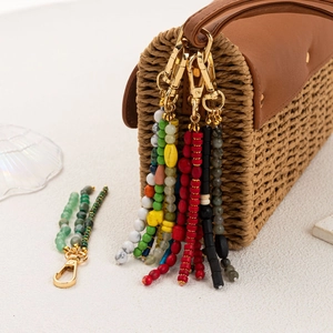 Bohemian beaded bag charms with colorful beads and tassels on a woven straw bag