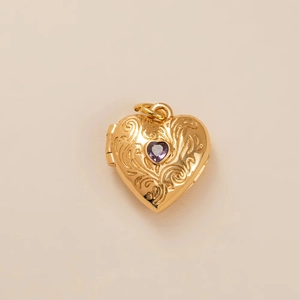 Detailed view of a vintage gold-plated heart locket featuring a purple zircon stone