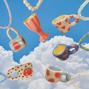 Colorful 18K gold-plated ceramic cup pendant necklaces floating against a bright sky blue background
