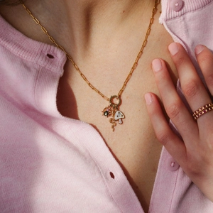Detail of gold chain necklace with insect, snake and mushroom charms on a model