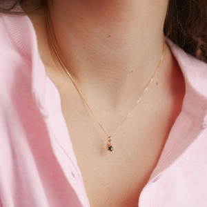 Close-up of model wearing heart-shaped pendants with pink and black gems on gold chain