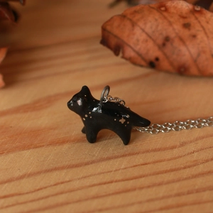 Vista macro di un ciondolo a forma di gatto smaltato nero con macchie dorate