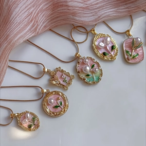 Dettaglio di ciondoli in acciaio dorato 18K con madreperla rosa e decori di perle