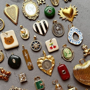 Dettaglio di ciondoli vintage in acciaio inossidabile placcato oro 18K con smalto e pietre