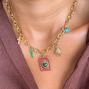 Gros plan détaillé du collier doré avec pendentifs croix, scarabée et mauvais œil