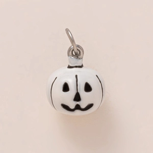 Détail macro d'un pendentif citrouille en émail blanc avec visage de Jack-o'-lantern