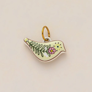 Detail of bird pendant charm with hand-painted floral patterns and 18K gold plating