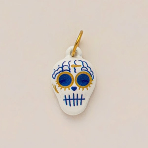 Detail of Day of the Dead skull charm in white ceramic with blue and gold floral patterns