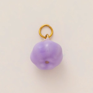 Macro shot of a purple glass pumpkin charm with a gold-plated stainless steel connector ring
