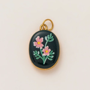 Detail of vintage 18K gold plated oval pendant with pink floral pattern on black enamel