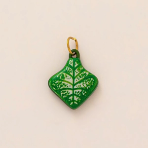Gros plan du pendentif feuille en émail vert avec anneau doré et détails de nervures
