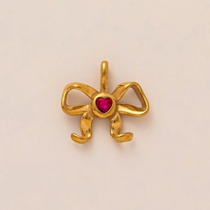 Gros plan d'un pendentif nœud doré orné d'une pierre précieuse rouge en forme de cœur