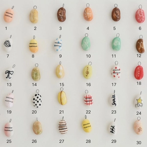 Vista detallada de 30 dijes coloridos hechos a mano con diversos diseños de arte