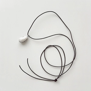 Collar minimalista con colgante de guijarro blanco y cordón marrón en fondo blanco