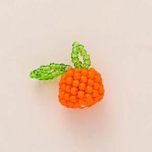 Detail of handcrafted orange bead charm featuring vibrant orange beads and green leaf accents