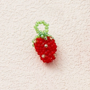 Detailed macro view of a handmade beaded strawberry pendant with red and green crystals