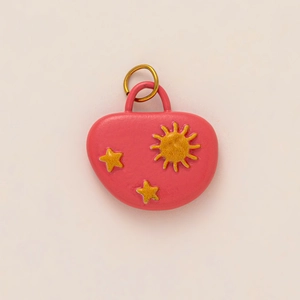 Detailansicht eines rosa Herzanhängers mit Goldsonnenrelief und 18k vergoldetem Ring