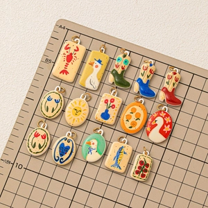 Handcrafted artistic pendants with nature motifs including swans and fruits on a cutting mat