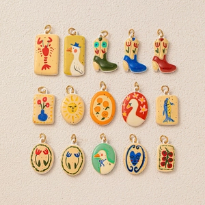 Set of 15 artistic illustrated pendants including heart and floral enamel charms