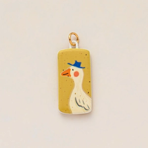 Close-up of yellow rectangular pendant featuring a cute white goose with blue hat