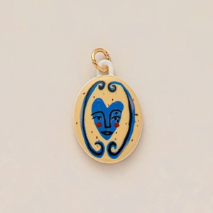 Macro view of oval ceramic pendant with blue heart face pattern and golden loop