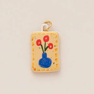 Macro view of rectangular ceramic pendant with red flowers in blue vase and gold ring