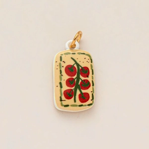 Close-up of ceramic rectangle charm featuring hand-painted red tomato pattern and gold ring