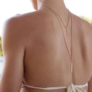 Double-layered gold back necklace with vertical bar pendants on a white backless dress