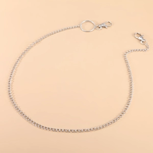 Silver curb chain pants link with spring ring and lobster clasps on beige background