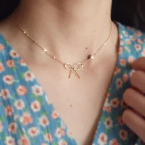 Elegant gold bow choker necklace for women worn by a model in a floral dress