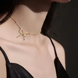 Elegant gold bow choker necklace with small beads on a model's collarbone