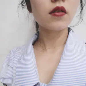 Minimalist gold bow choker necklace for women shown on a model with a casual striped shirt