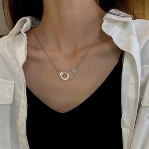 Macro shot of silver handcuff necklace on model, featuring small polished metal pendants