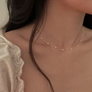 Close-up of minimalist gold chain necklace with small white pearls on a model neck