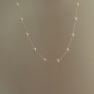 Elegant gold choker necklace with delicate white beads for a minimalist fashion look