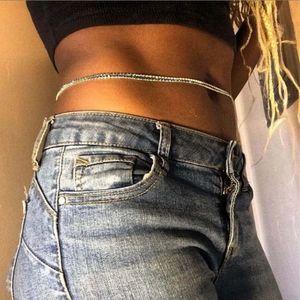 Detail view of a slim silver body chain with zircon fringe on a casual denim outfit