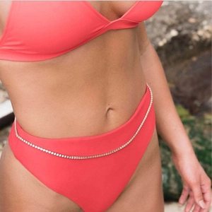 Detail of silver body chain with single row zircons on waist over red bikini