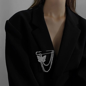 Detail of silver butterfly pin brooch with layered metal chains on black suit lapel