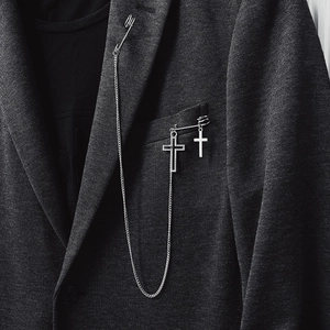 Broche croix punk argentée avec longue chaîne à maillons sur un blazer gris foncé