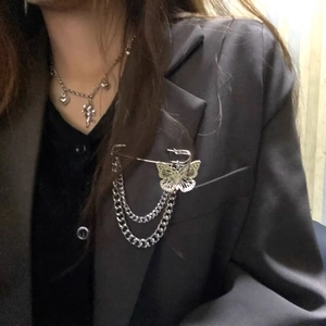 Detail of silver butterfly brooch with double chains and heart pendant necklace on a blazer