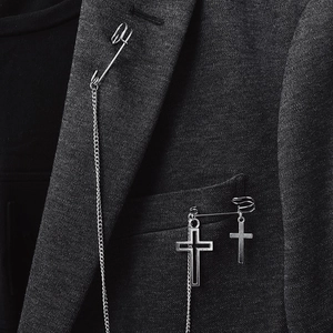 Gros plan sur une broche punk argentée avec croix sur le revers d'un costume noir
